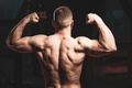 Man flexing his muscles inside a gym to display his muscular definition and progress from strength training