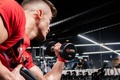 Man exercising in a gym while lifting a dumbbell with one arm to perform a biceps curl
