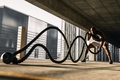 Man exercising outdoors with heavy battle ropes during a physically demanding strength and conditioning workout