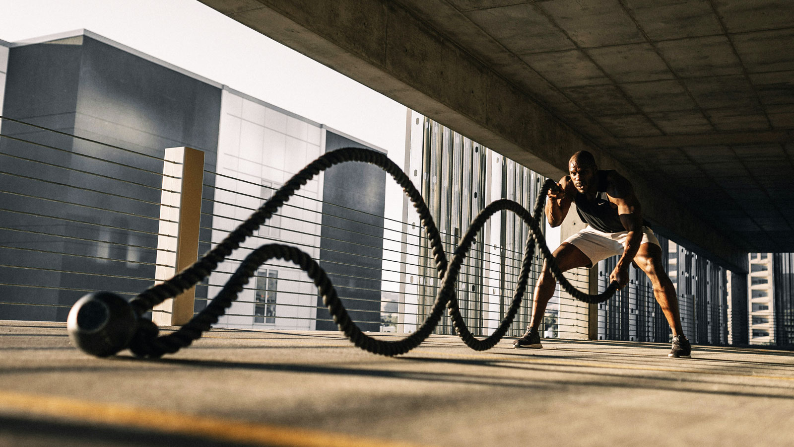 Man exercising outdoors with heavy battle ropes during a physically demanding strength and conditioning workout