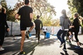 Group of people exercising on an outdoor paved surface while following an instructor demonstrating leg movements during a fitness warm-up