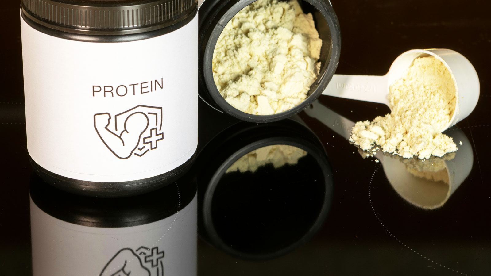 Container of vanilla-flavored protein powder with a measuring scoop arranged against a black background for a fitness nutrition setup