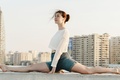 Woman wearing a black long-sleeved shirt performing a yoga pose that demonstrates flexibility and controlled body movement